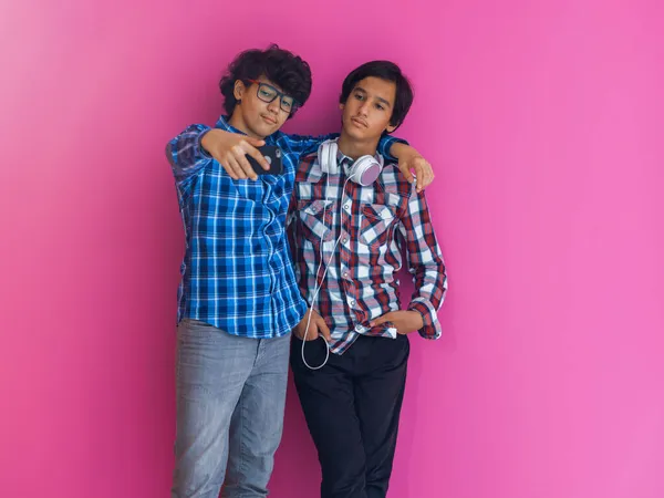 Foto de un adolescente árabe joven tomando una foto selfie con un teléfono inteligente aislado detrás de una pared púrpura. Enfoque selectivo —  Fotos de Stock