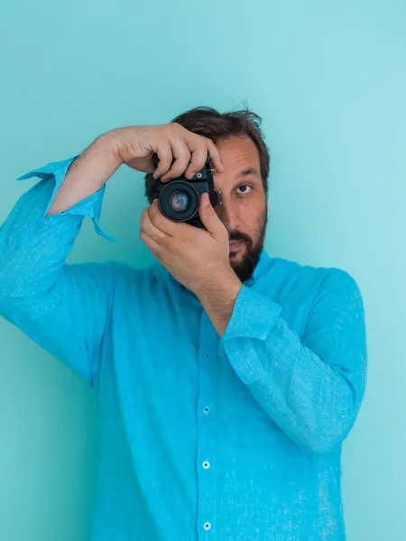 Porträt eines männlichen Fotografen in blauem Hemd, der eine alte analoge Slr-Kunstkamera hält, während er vor zyanischem Hintergrund steht — Stockfoto