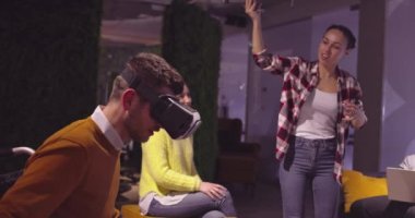 Modern açık uzay ofisinde çalışan engelli bir iş adamı sanal gerçeklik gözlüğü ve İHA simülasyonu kullanarak takım toplantısı yapıyor. Girişim işinde etkin takım çalışması.