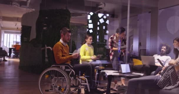 Homme d'affaires handicapé en fauteuil roulant au travail dans un bureau moderne de coworking en espace ouvert lors d'une réunion d'équipe utilisant des lunettes de réalité virtuelle et une simulation de drone. Travail d'équipe efficace dans une entreprise en démarrage. — Video