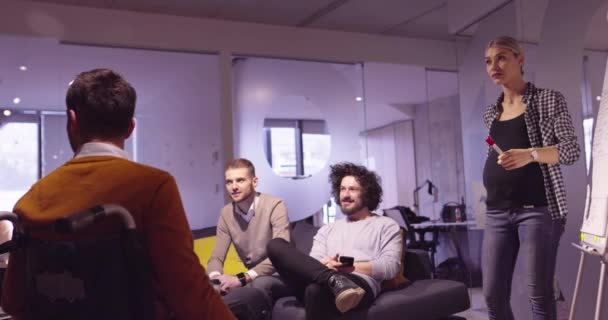 Behinderter Geschäftsmann im Rollstuhl bei der Arbeit in einem modernen Coworking-Büro im offenen Raum bei einem Teammeeting. Effektive Teamarbeit und Einbindung in ein Start-up-Unternehmen. — Stockvideo