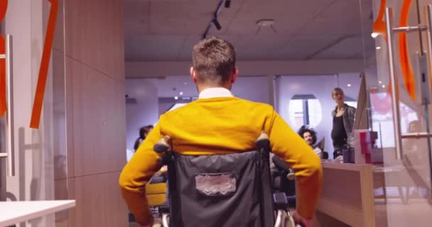 Zdravotně postižený podnikatel na invalidním vozíku při práci v moderní open space kooperativní kanceláři na týmové schůzi. Účinná týmová práce a začlenění do začínajícího podnikání. — Stock video