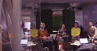 Modern bir açık alanda çalışan Müslüman bir kadın takıma bir sunum yapıyor. Orta Doğulu Arap iş kadını yaratıcı bir ofiste. Ekip toplantısında tekerlekli sandalyedeki engelli iş adamı 