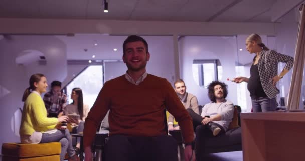 Behinderter Geschäftsmann im Rollstuhl bei der Arbeit in einem modernen Coworking-Büro im offenen Raum bei einem Teammeeting. Effektive Teamarbeit und Einbindung in ein Start-up-Unternehmen. — Stockvideo