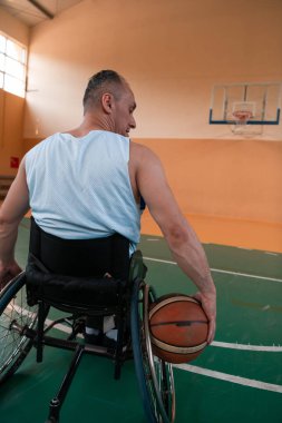 Tekerlekli sandalye ve engelli savaş gazilerinin sahada basketbol oynarken çekilmiş yakın bir fotoğrafı. Seçici odak 