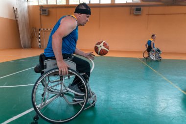 Engelli savaş gazileri ve tekerlekli sandalyeli yaş basketbol takımları spor salonunda antrenman yapıyorlar. Özürlülerin rehabilitasyonu ve kapsama konsepti