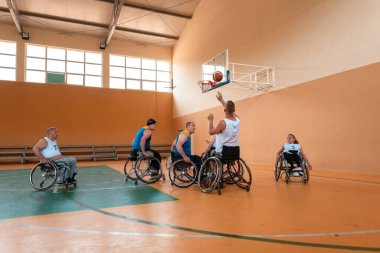 Engelli savaş gazileri ve tekerlekli sandalyeli yaş basketbol takımları spor salonunda antrenman yapıyorlar. Özürlülerin rehabilitasyonu ve kapsama konsepti