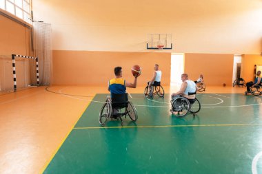 Engelli savaş gazileri ve tekerlekli sandalyeli yaş basketbol takımları spor salonunda antrenman yapıyorlar. Özürlülerin rehabilitasyonu ve kapsama konsepti
