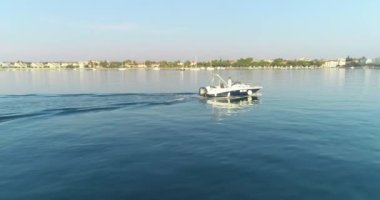 Mutlu bir ailenin yaz tatilinde sabahın erken saatlerinde açık denizde lüks bir tekne sürüşünün insansız hava aracı görüntüsü.