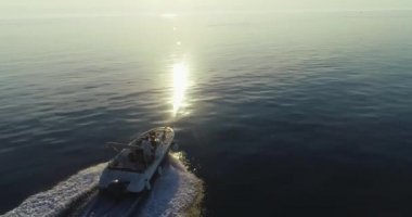 Mutlu bir ailenin yaz tatilinde sabahın erken saatlerinde açık denizde lüks bir tekne sürüşünün insansız hava aracı görüntüsü.