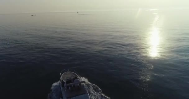 Un tiro de dron de una familia feliz en unas vacaciones de verano conduciendo un barco de lujo en alta mar en la madrugada — Vídeos de Stock