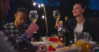 Akşamları yemek masasında bir grup arkadaş açık havada beraberler. 