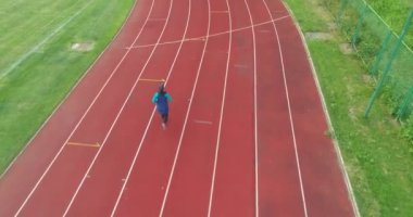 Genç Arap sporcunun tesettürlü atletik vücudu ile stadyum atletizm pistinde koşuşunun sinematik çekimi. Kavram: kararlılık, kadın gücü, hedef başarısı. Yüksek kalite 4k görüntü