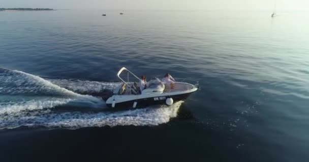 Ένα drone πλάνο μιας χαρούμενης οικογένειας σε καλοκαιρινές διακοπές οδηγώντας ένα πολυτελές σκάφος στην ανοιχτή θάλασσα στο ηλιοβασίλεμα. — Αρχείο Βίντεο