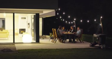 Akşamları yemek masasında bir grup arkadaş açık havada beraberler. 