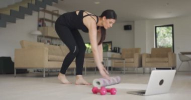 Koronavirüs salgını sırasında beden eğitimi hocası evde online eğitim yapmak için bir dizüstü bilgisayar ve egzersiz ekipmanı hazırlayın.