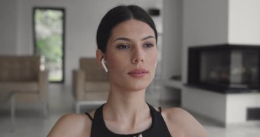 Spor giyim sektöründe karışık bir yarış kadını dizüstü bilgisayarda yoga eğitimi alırken esneme egzersizleri yapıyor. Arka planda kanepe ile oturma odasında egzersiz yapan sağlıklı bir kız..