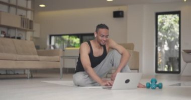 Afrikalı Amerikan fitness eğitmenleri dizüstü bilgisayarı müşteriyle çevrimiçi eğitim için ya da koronavirüs salgını sırasında çevrimiçi fitness dersi için kullanırlar. Yüksek kalite 4k görüntü