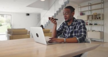Afro-Amerikalı iş adamı akıllı telefon ve laptop kullanarak online konferans videosu çekiyor. Erkek Çağrı Merkezi Ajanı, İnsan Kaynakları Müdürü web kamerasından iş görüşmesi ya da modern bir evde toplantı yapıyor.