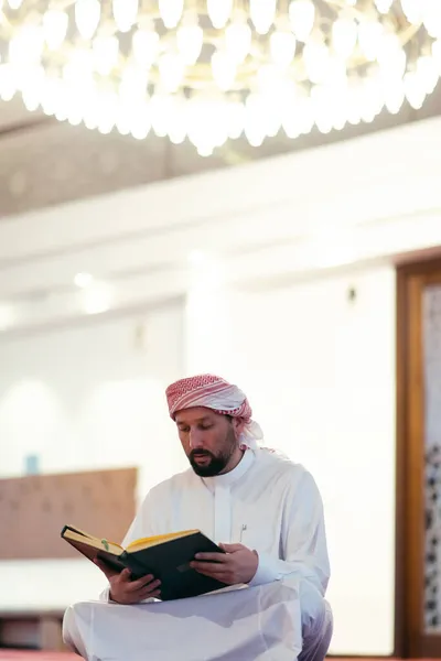 Homem muçulmano orando Alá sozinho dentro da mesquita e lendo livro azevinho islâmico — Fotografia de Stock