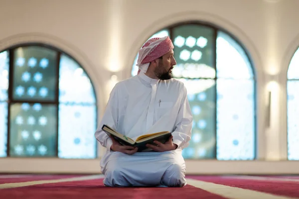 Hombre musulmán rezando Allah solo dentro de la mezquita y leyendo el libro de acebo islámico — Foto de Stock