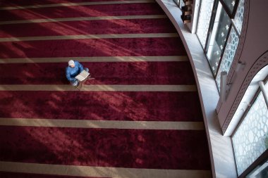 Müslüman adam camide tek başına Allah 'a dua ediyor ve Kuran-ı Kerim' i okuyor.