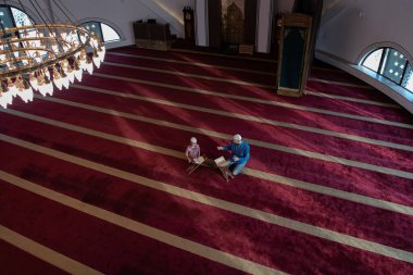 Müslüman dua eden baba ve oğul camide dua eder ve kutsal kitap Kuran okurlar. 