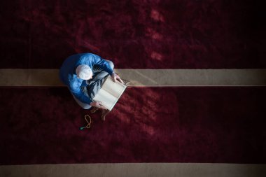 Müslüman adam camide tek başına Allah 'a dua ediyor ve Kuran-ı Kerim' i okuyor.