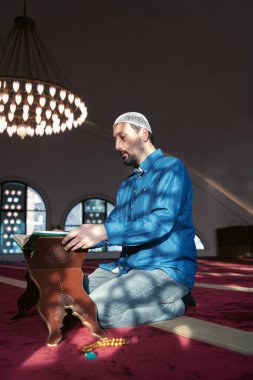 Müslüman adam camide tek başına Allah 'a dua ediyor ve kutsal Kuran' ı okuyor.