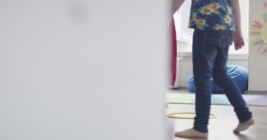Küçük anaokulu öğrencileri ve bayan öğretmenleri sınıfın içinde egzersiz yapıyorlar. Hula hoop pistinin üzerinden zıplıyordu. Yüksek kalite 4k görüntü