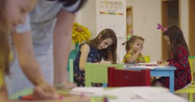 Bir kreşteki sanat dersinde yaratıcı çocuklar ya da ilkokul sınıfında bayan öğretmenle resim çizen çocuklar. Ağır çekim. Yüksek kalite 4k görüntü