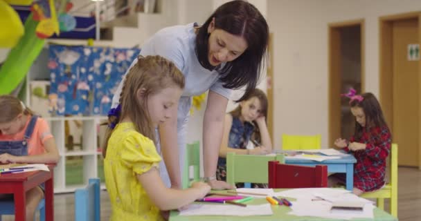 在日托中心的艺术课或小学课堂上与女教师一起画画时 有创意的孩子 慢动作高质量的4K镜头 — 图库视频影像