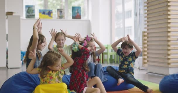 Storytime basis- of basisschoolleraar die een verhaal voorleest aan een groep kinderen in een kinderdagverblijf. — Stockvideo