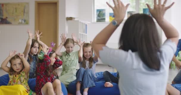 Storytime basis- of basisschoolleraar die een verhaal voorleest aan een groep kinderen in een kinderdagverblijf. — Stockvideo