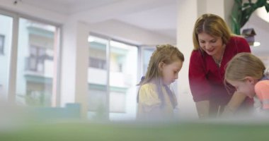 Bir kreşteki sanat dersinde yaratıcı çocuklar ya da ilkokul sınıfında bayan öğretmenle resim çizen çocuklar. Ağır çekim. Yüksek kalite 4k görüntü