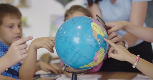 Profesora con niños en clase de geografía mirando al mundo. Vista lateral del grupo de diversos niños felices de la escuela con el mundo en el aula en la escuela. — Vídeos de Stock