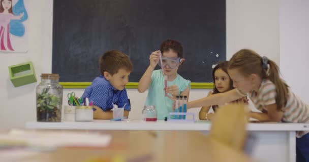 Науковий клас початкової школи: Захоплений вчитель пояснює хімію різноманітній групі дітей, маленький хлопчик змішує хімічні речовини в напоях. Діти вчаться з інтересами — стокове відео