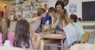 Coğrafya sınıfındaki coğrafya öğretmeni. Bir grup mutlu okul öğrencisinin yan görüntüsü. Okuldaki sınıflarında küre olan çocuklar..