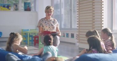 Öğretmen ilkokuldaki çocuklara kitap okuyor.