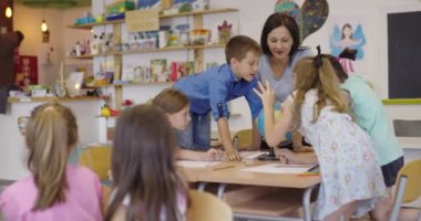 Coğrafya sınıfındaki coğrafya öğretmeni. Bir grup mutlu okul öğrencisinin yan görüntüsü. Okuldaki sınıflarında küre olan çocuklar..