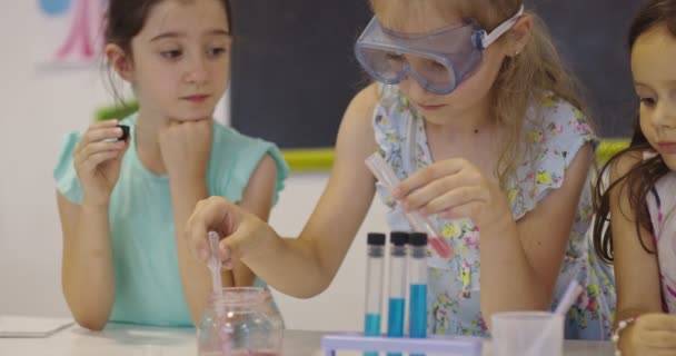 Aula de Ciencias de la Escuela Primaria: Profesor Entusiasta Explica Química a Diverso Grupo de Niños, Niño Pequeño Mezcla Químicos en Beakers. Niños aprenden con interés — Vídeo de stock