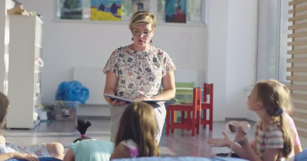 Professor lendo um livro para crianças no ensino fundamental — Vídeo de Stock