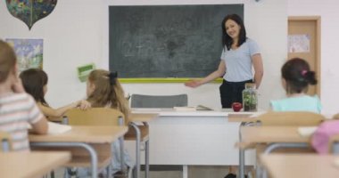 Öğretmen ilkokuldaki çocuklara kitap okuyor.