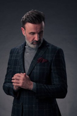 Gri sakallı, iş kıyafetleri içinde koyu renk arka planda el kol hareketleriyle izole edilmiş fotoğraf stüdyosuna güvenen başarılı, şık, zarif kıdemli bir işadamının portresi. Yüksek kaliteli fotoğraf.