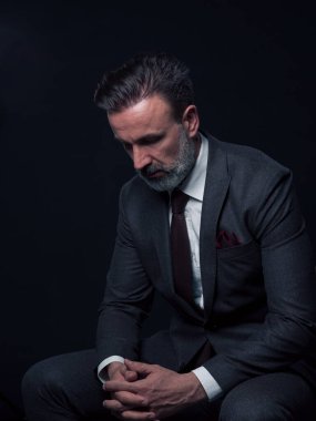 Yetişkin iş adamının son moda takım elbiseli portresi ve modern stüdyoda siyah arka planda şık bir sandalyede oturuyor. Yatay maketler. Yüksek kalite fotoğraf