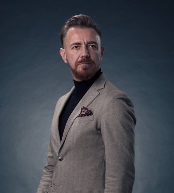 Gri sakallı, iş kıyafetleri içinde koyu renk arka planda el kol hareketleriyle izole edilmiş fotoğraf stüdyosuna güvenen başarılı, şık, zarif kıdemli bir işadamının portresi. Yüksek kaliteli fotoğraf.