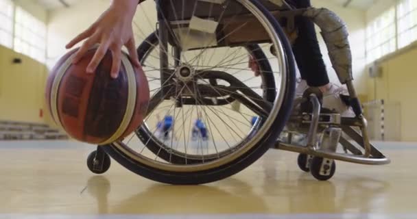 Une personne handicapée soulève un ballon de basket-ball du sol tout en s'entraînant dans un hall moderne — Video