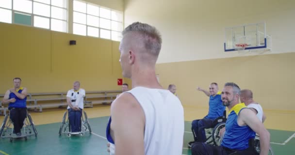 Osoby niepełnosprawne rozciągające się przed meczem koszykówki w nowoczesnej hali. Zwolniony ruch — Wideo stockowe
