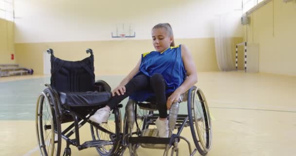 Una mujer con discapacidades jugador de baloncesto se prepara para un partido mientras está sentado en una silla de ruedas. Preparativos para un partido de baloncesto profesional. Imágenes de alta calidad 4k — Vídeos de Stock