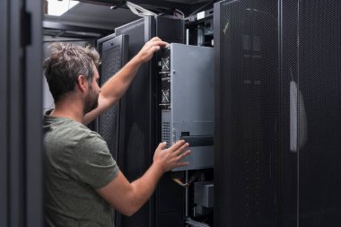 Bilgi işlem mühendisi sunucu odasında ya da veri merkezinde çalışıyor. Teknisyen bir rafa koyarak şirket ana bilgisayarının yeni sunucusunu ya da kripto para birimi çiftliğini kurar.. 